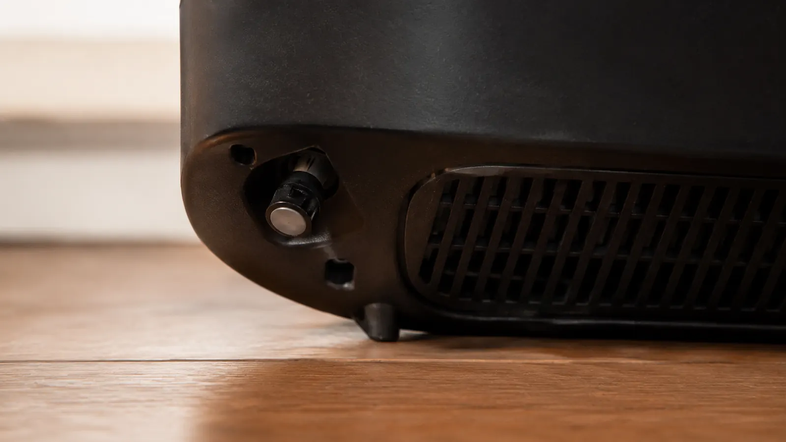 Close-up of the tip-over safety switch and vented back panel on a small black ceramic heater