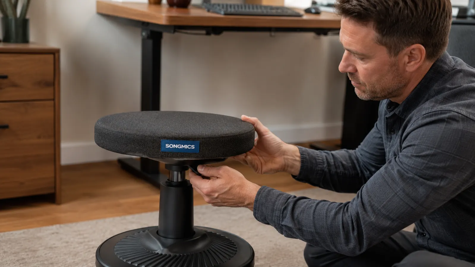 Close-up of a hand pressing the height adjustment lever on the SONGMICS wobble stool base