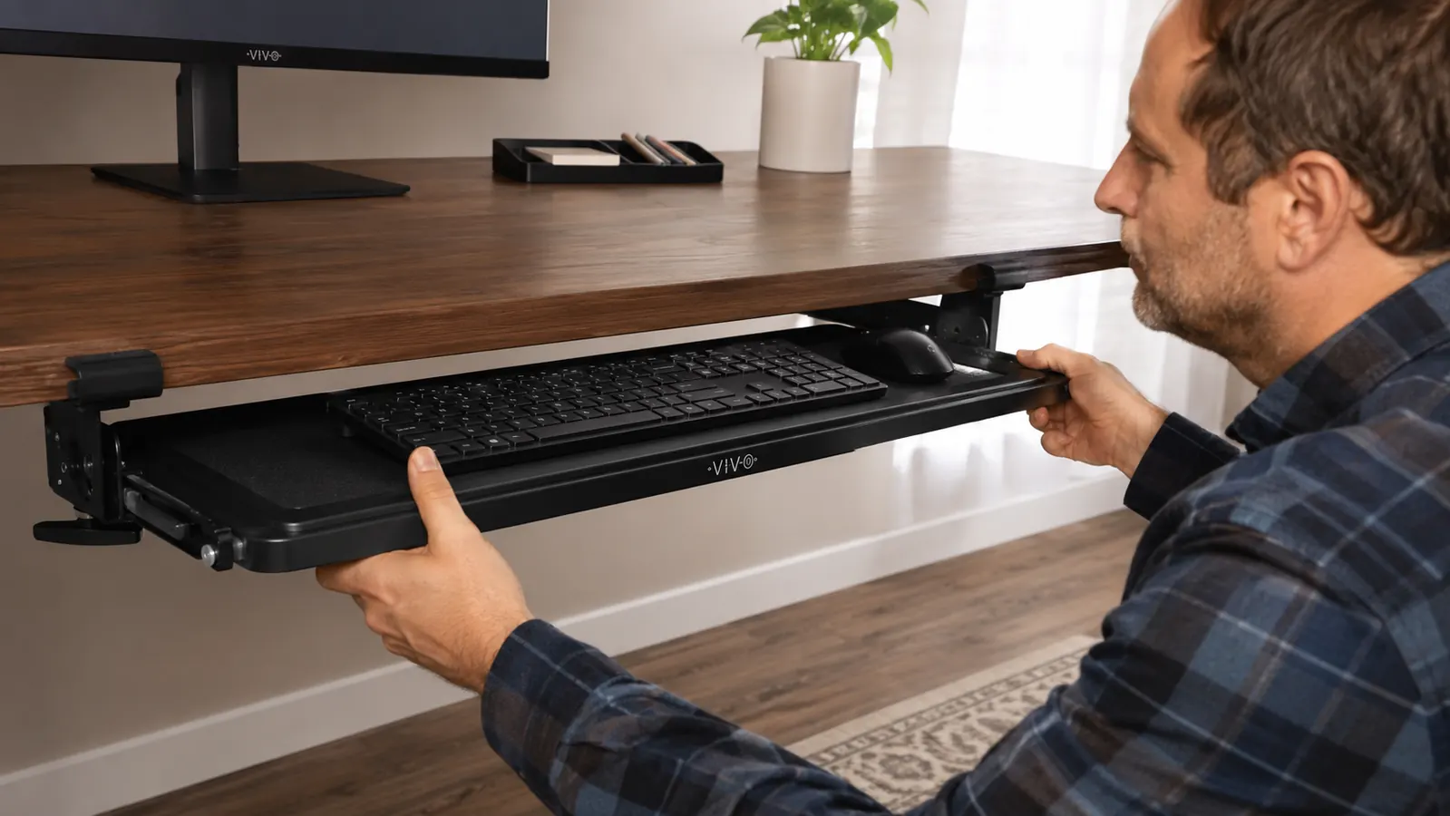 Hand sliding a black keyboard tray back under a desk after typing