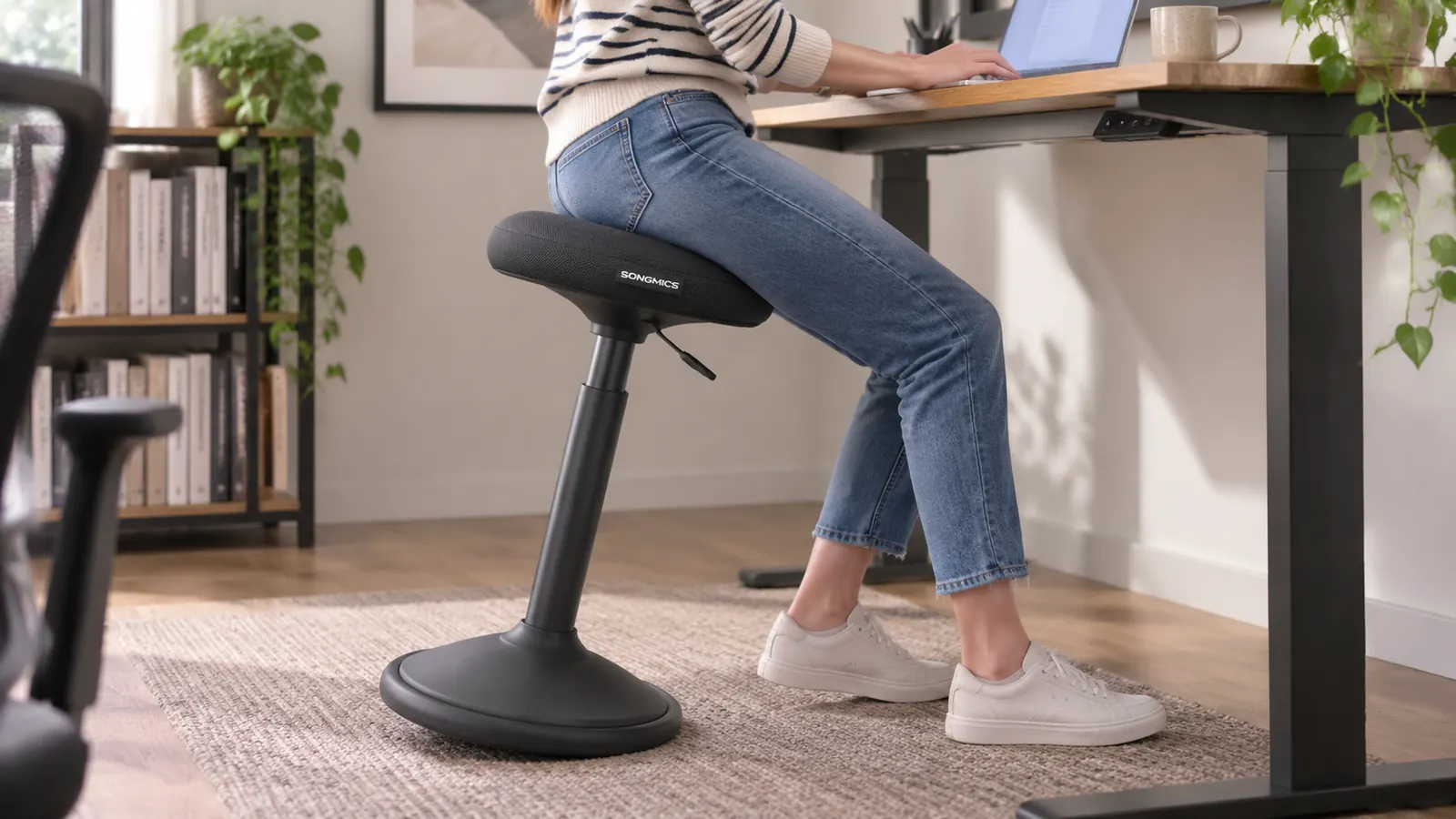 Close-up of a black wobble stool base tilted at an angle beside a standing desk